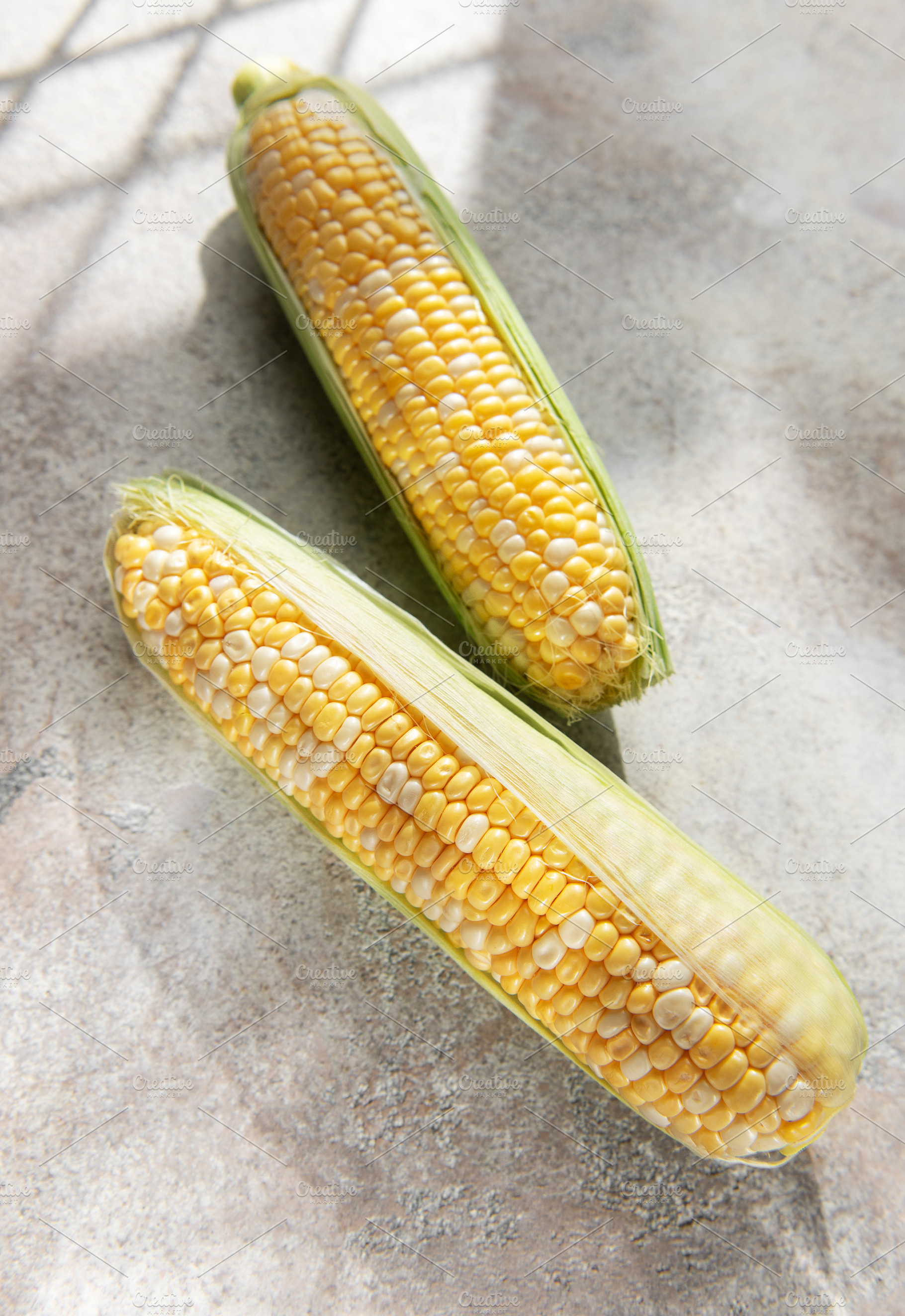 Fresh corn cobs on concrete background, a Food & Drink Photo by Olena Rudo