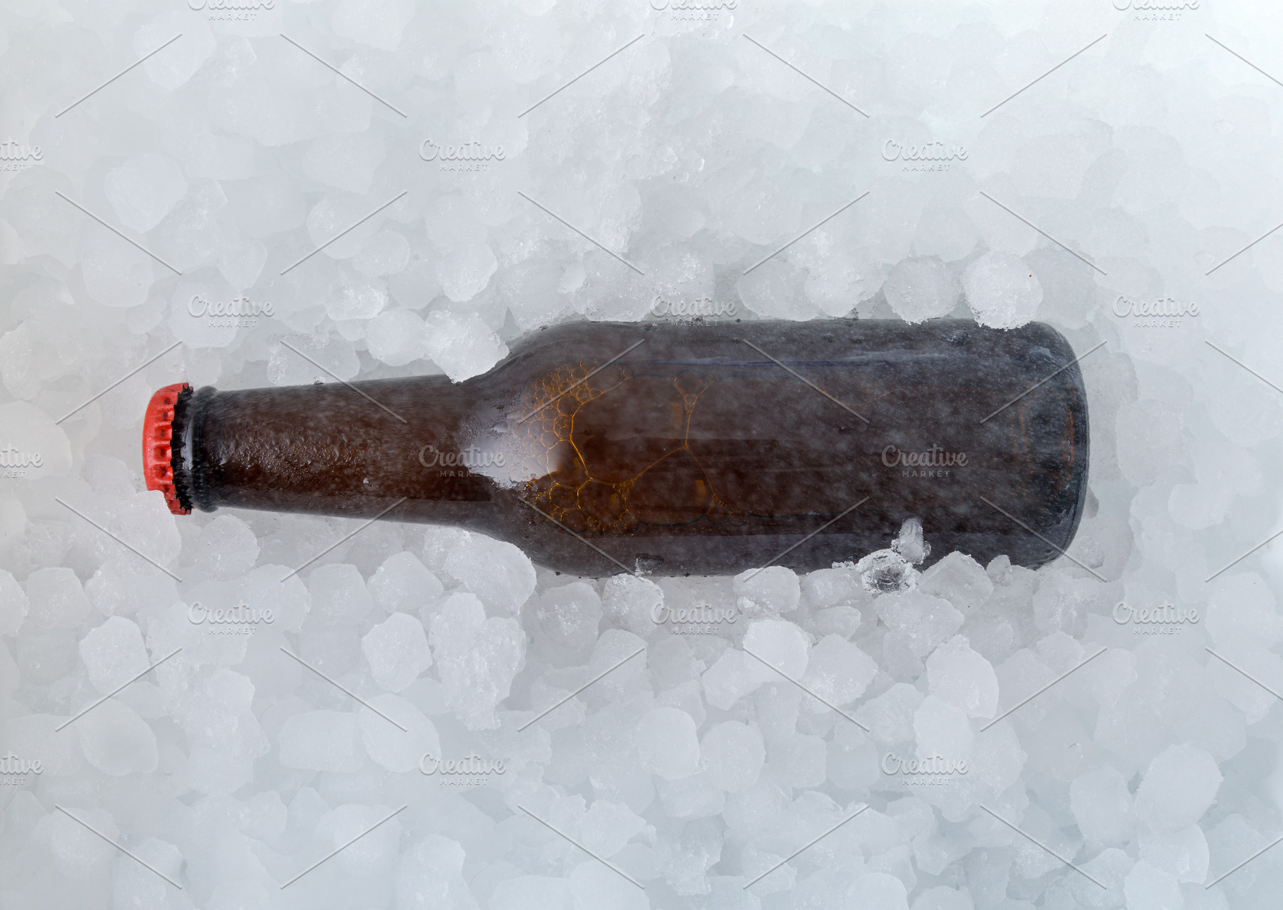 Brown beer bottle buried in a pile of ice cubes, a Food & Drink Photo by Davizro's Market