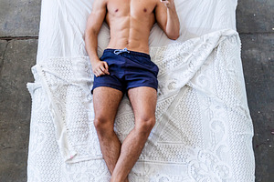 Young man relaxing in bed while using smartphone at home, a Person Photo by RF Images