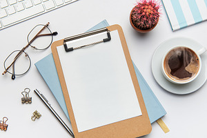 Clipboard with blank paper, coffee, cactus and office supplies o, a Business Photo by Olena Rudo