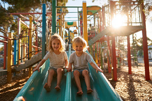 Happy kids sliding down playground s, a Photo by Pixeness Studio