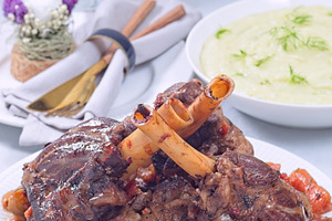 Delicious braised lamb shanks with vegetables on a white plate, vertical, a Food & Drink Photo by iuliia_n