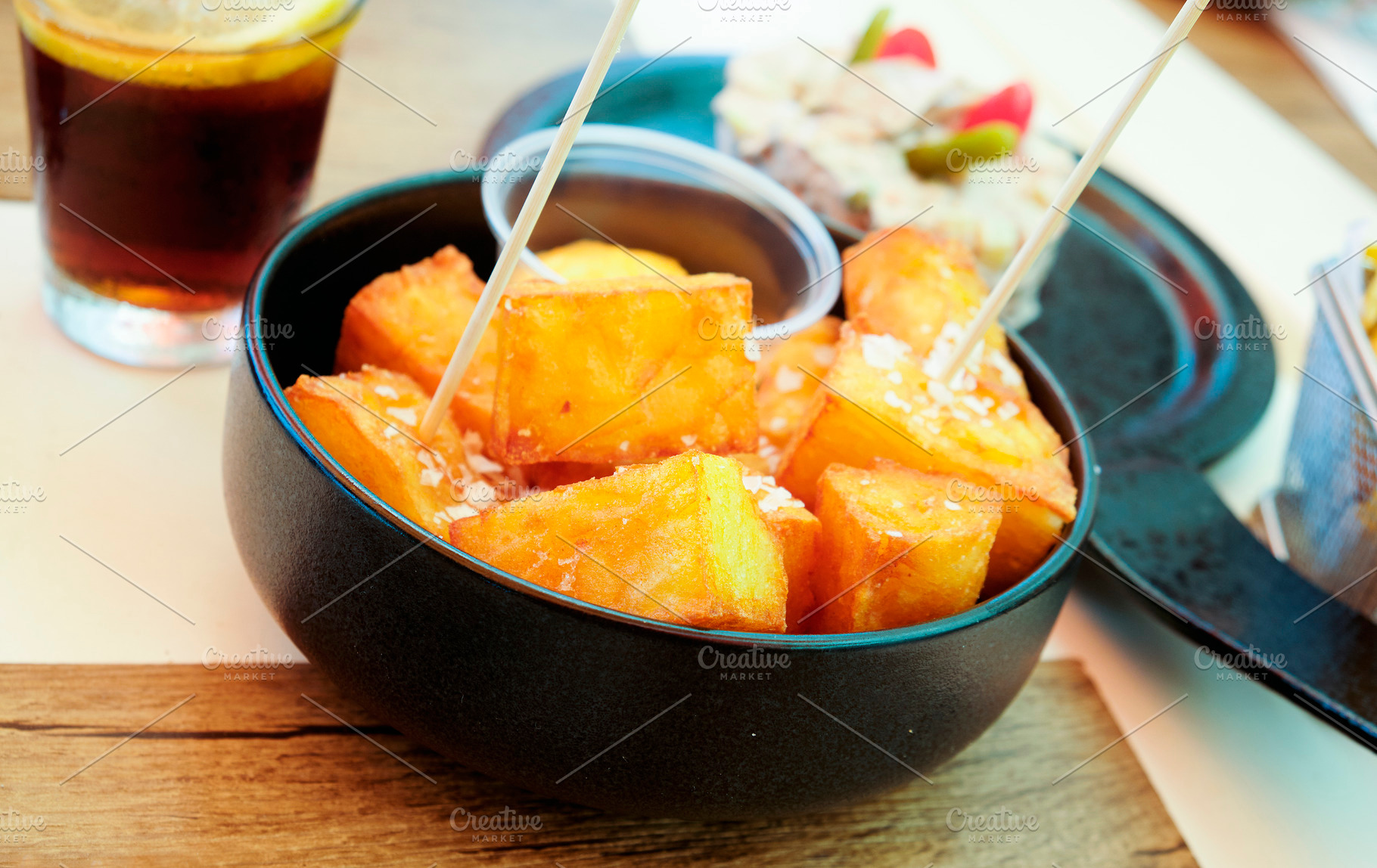 a bowl of spanish patatas bravas on a table, a Photo by Nito
