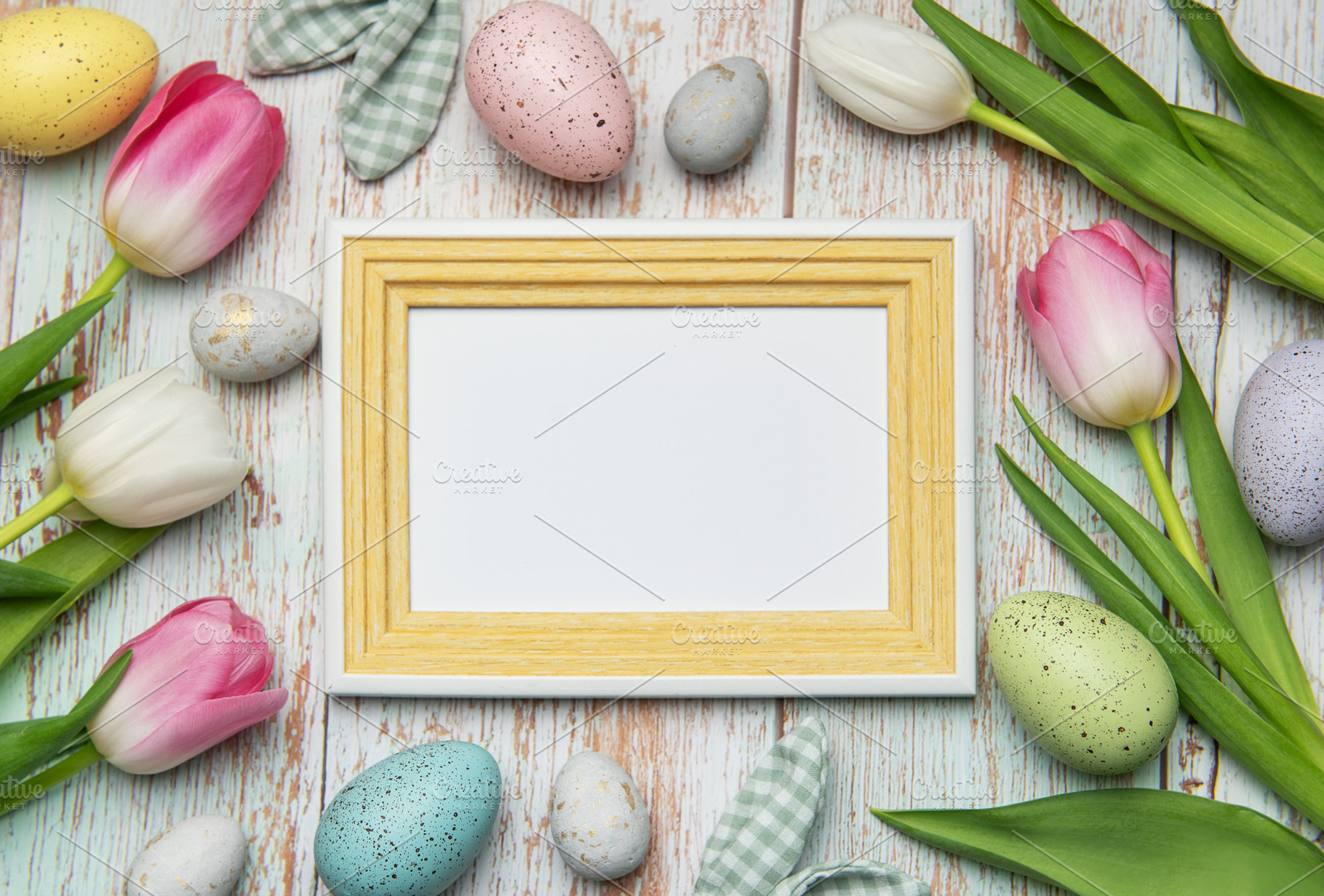 Easter eggs and tulips framing blank picture frame on wooden bac, a Holiday Photo by Olena Rudo