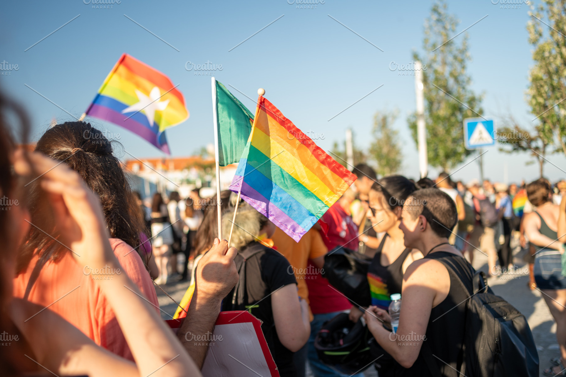 Crowd of homosexual men and women with rainbow flags at pride parade, a Photo by andreonegin market