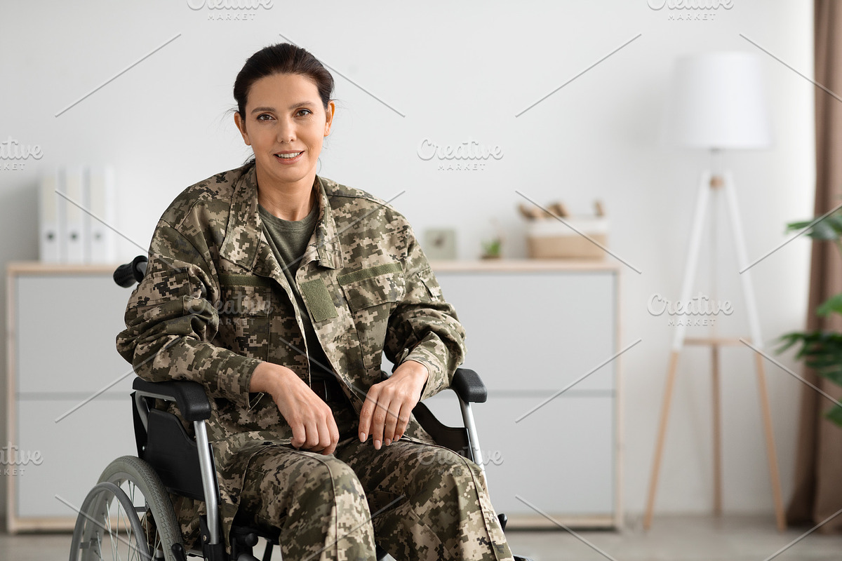Portrait Of Smiling Female Soldier In Camouflage Uniform Sitting In Wheelchair, a Photo by Prostock-Studio (Photo 1 of 2)