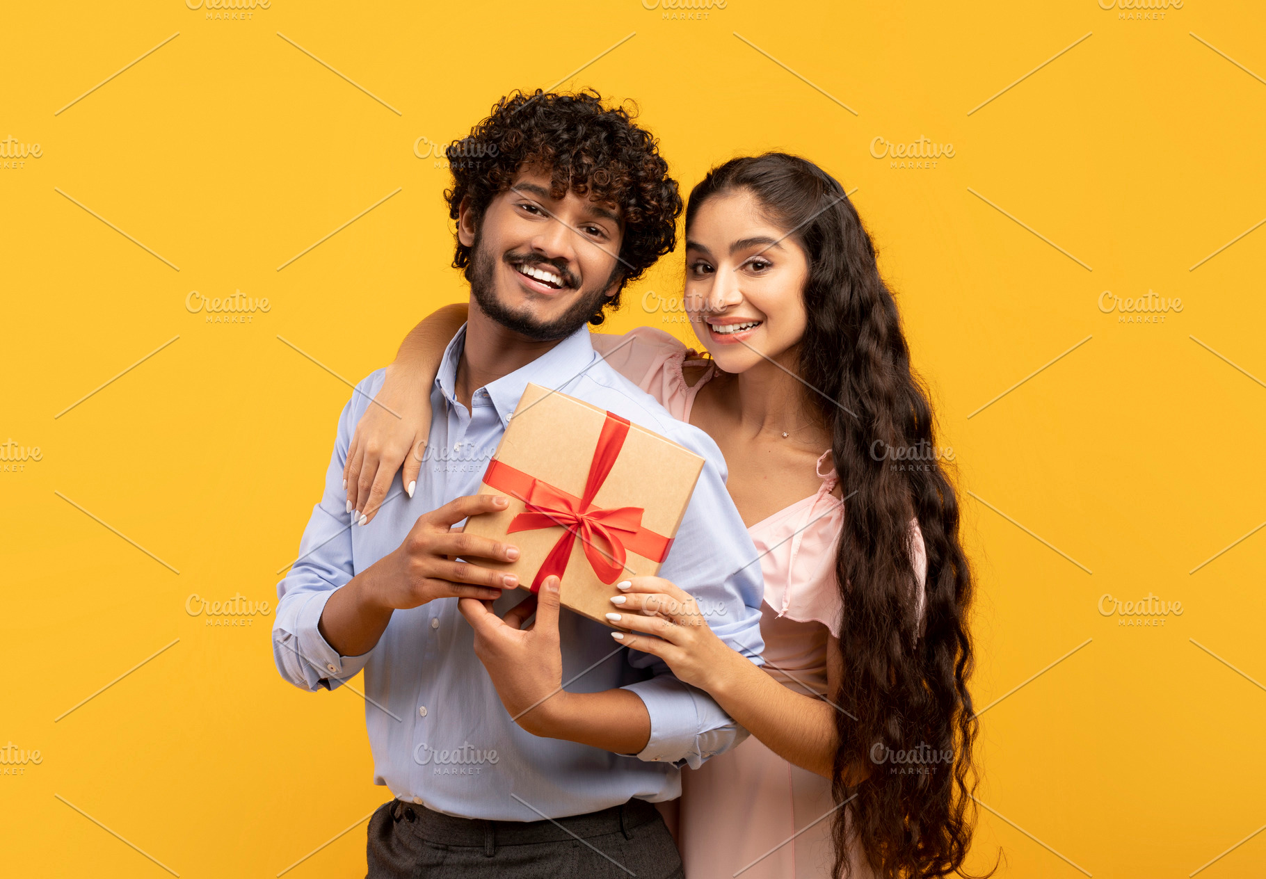 Portrait of loving indian couple holding wrapped gift for Valentine's Day toget, a Person Photo by Prostock-Studio