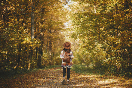 Stylish woman hipster with backpack in hat walking in sunny autu, a Person Photo by Sonjachni
