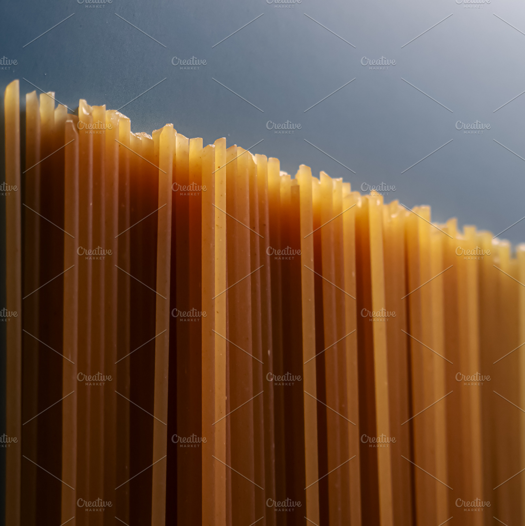 Dry whole wheat spaghetti pasta standing upright, creating an abstract textured, a Photo by Studio ANNA
