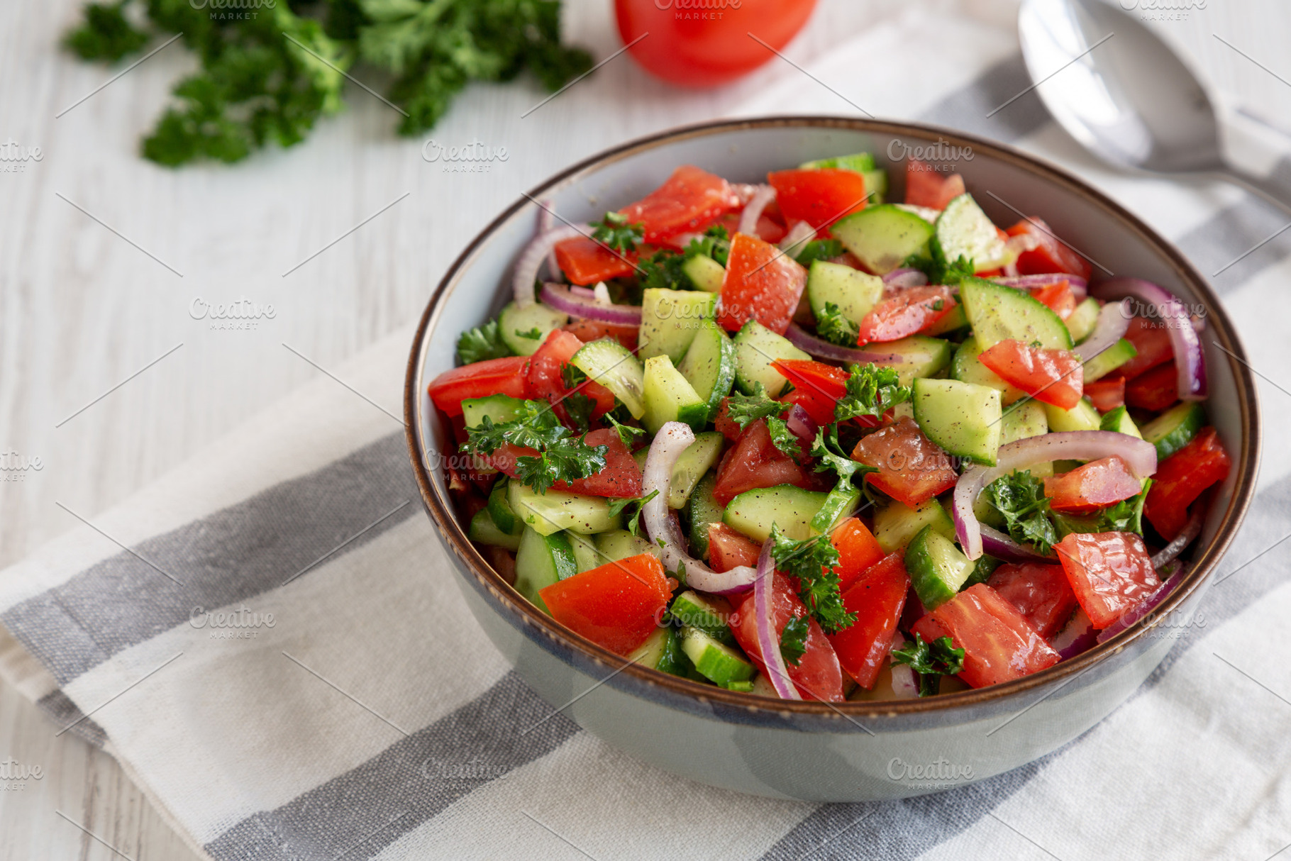 Homemade Mediterranean Cucumber Tomato Salad in a Bowl, side vie, a Food & Drink Photo by LiudmylaChuhunova