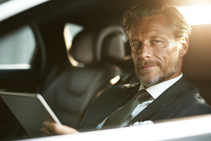 Man in suit reading tablet in car, a Photo by Beautiful things
