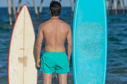 Surfer standing on beach with surfboard