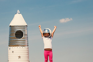 Happy child dressed in an astronaut costume playing with hand ma featuring