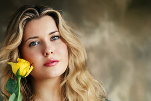 Young woman holding yellow rose, looking at camera, representing, a Person Photo by Studio ANNA