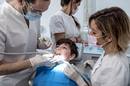 Team of dentists treating a young boy for orthodontics in the dentist's clinic, a Health & Medical Photo by RF Images