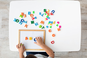Foreign language classes. Top view of kid making ABC note with colorful English, a Photo by Prostock-Studio