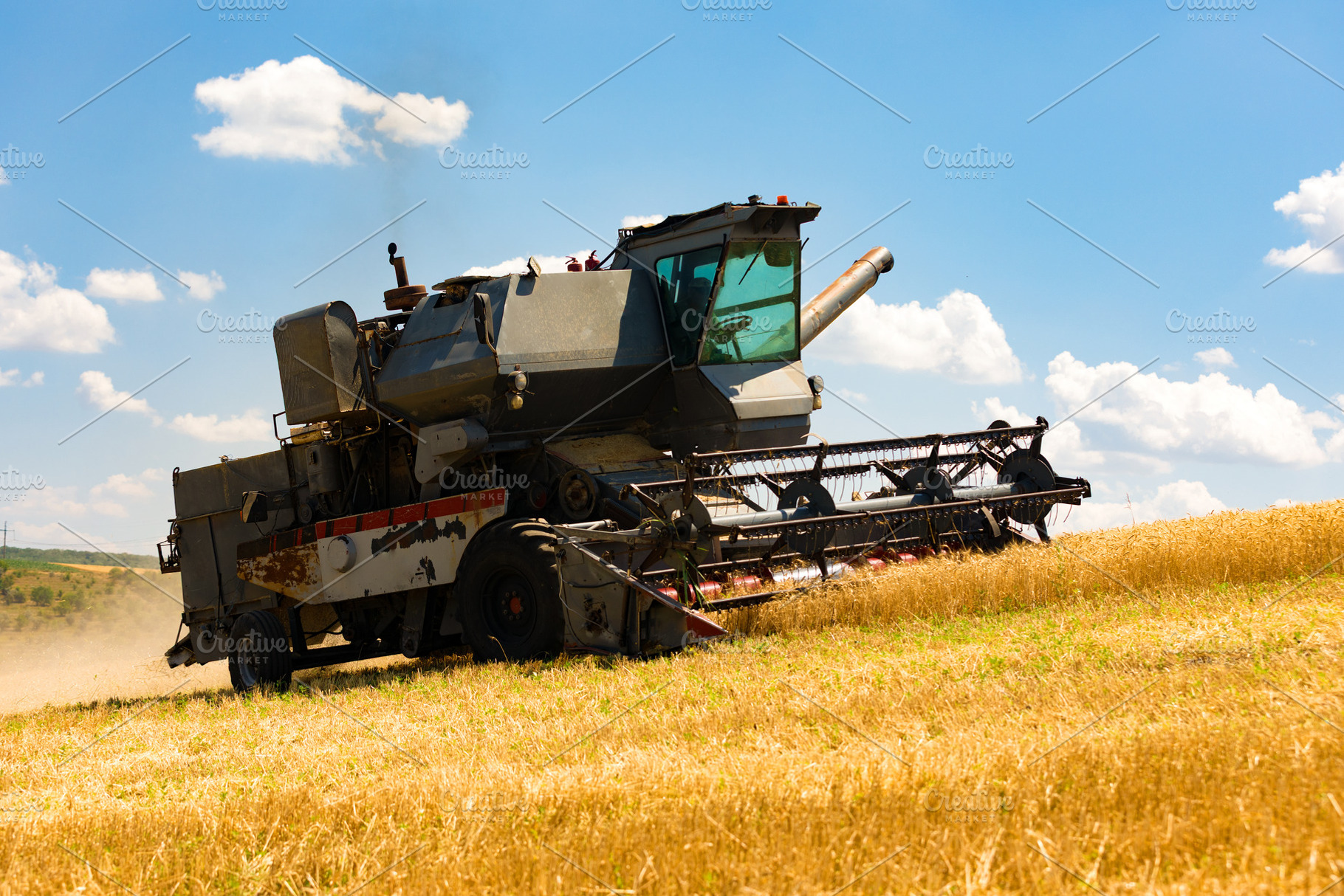 Aged agricultural combine harvesting golden wheat on a sunny day, a Transportation Photo by Ales Munt