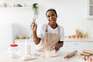 Laughing millennial african american woman in apron prepares dough for baking a, a Person Photo by Prostock-Studio