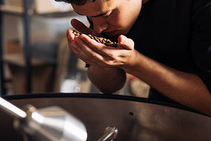 Young barista smelling coffee beans, a Food & Drink Photo by Artem Varnitsin