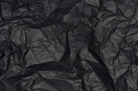 Crumpled sheet of black parchment paper, abstract background, an Abstract Photo by ndanko