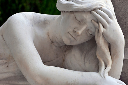 statue of a sad woman in cemetery
