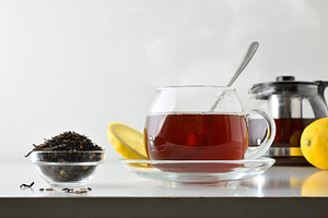 Black tea with lemon on white table isolated front view, a Food & Drink Photo by Davizro's Market