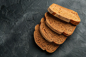 Sliced baked rye bread on black background, a Food & Drink Photo by AlyaAnd