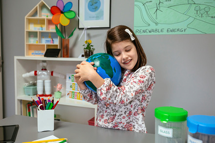 Female student hugging a handmade globe world at ecology classroom, a School & Education Photo by davidpereiras