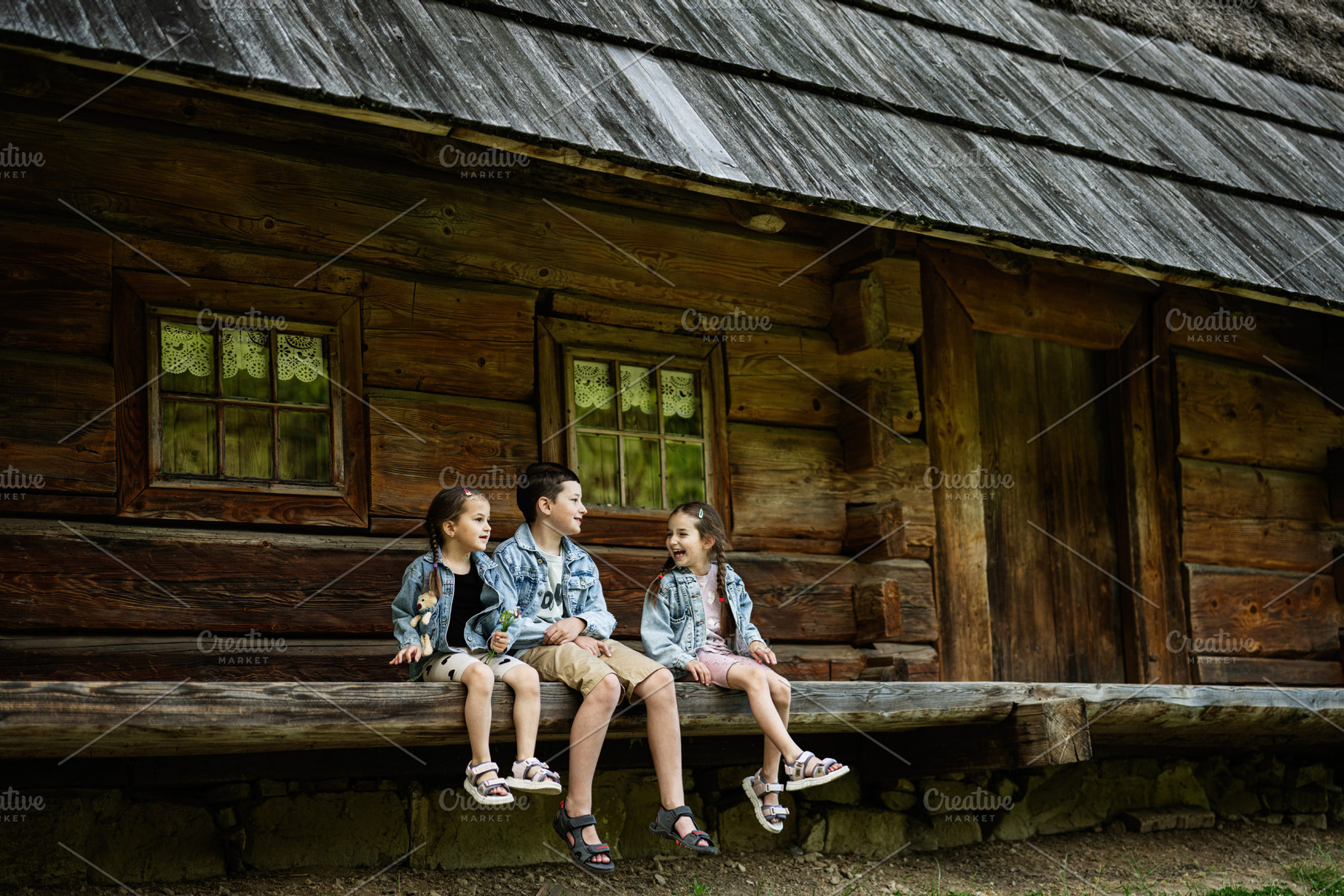 Children Sitting on Wooden Bench Near Rustic Cabin in Outdoor Setting, a Person Photo by AS photostudio