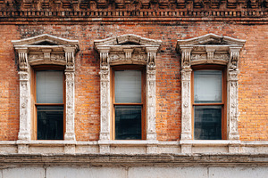 Ornate windows on a vintage brick facade, an Architecture Photo by AlyaAnd