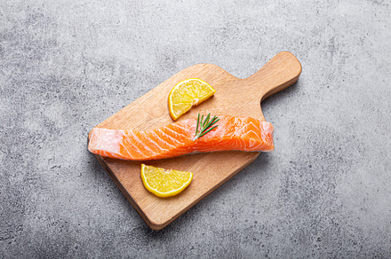 Raw salmon fish fillet with lemon wedges and rosemary on wooden, a Food & Drink Photo by its_al_dente