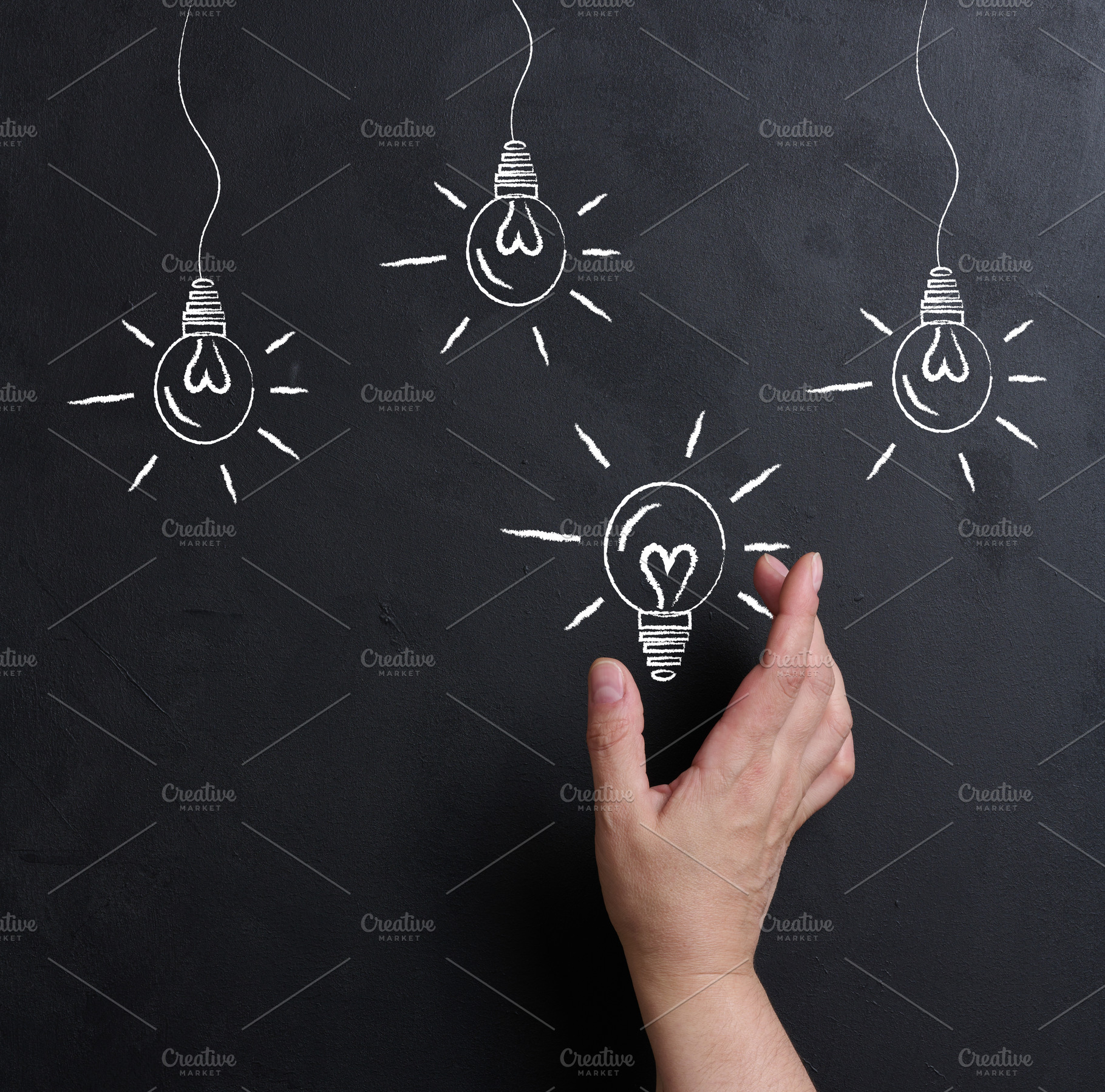 A hand reaches out to a chalk-drawn glowing light bulb on a blac, a Business Photo by ndanko