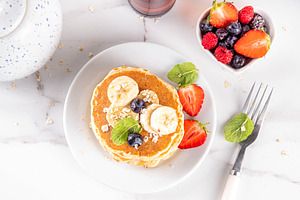 Stack of tasty healthy oatmeal pancakes with banana and fresh be, a Food & Drink Photo by Rimma