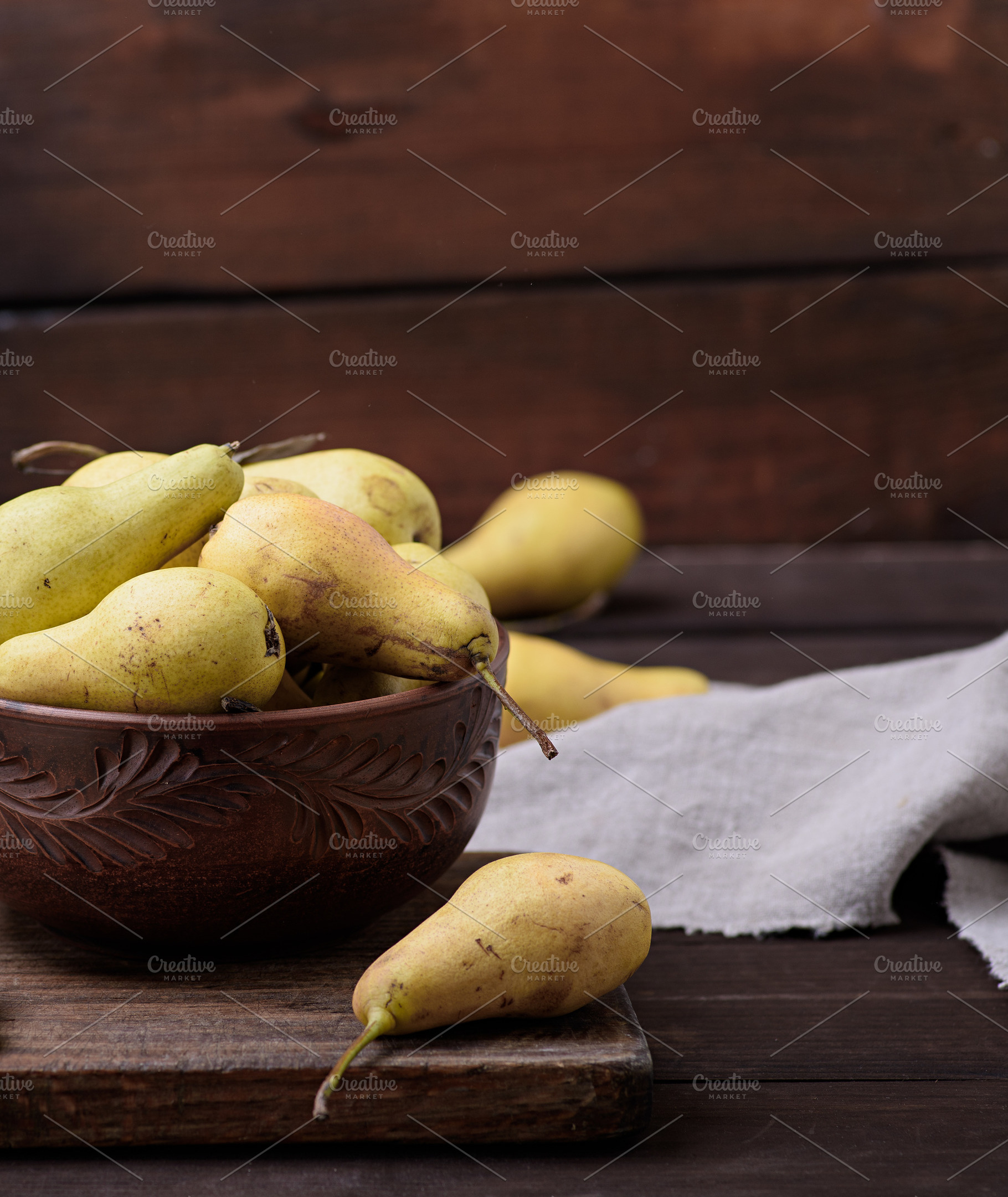 Ripe yellow green pears in a brown ceramic bowl on a wooden tabl, a Food & Drink Photo by ndanko