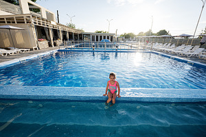 Young child enjoying a sunny day by the swimming pool outdoors, a Photo by AS photostudio