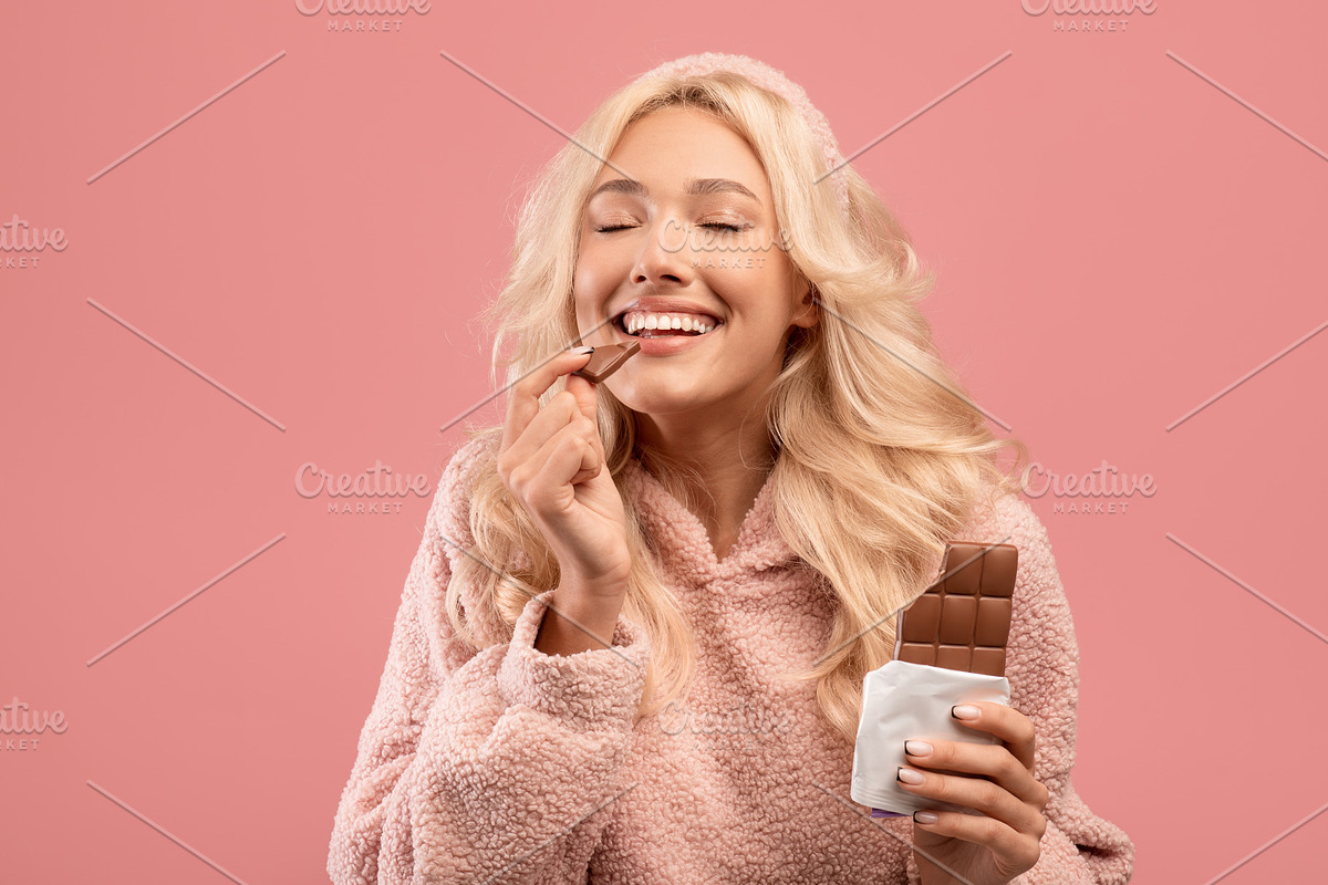 Young caucasian lady eating chocolate, enjoying yummy dessert with closed eyes,, a Photo by Prostock-Studio (Photo 2 of 2)