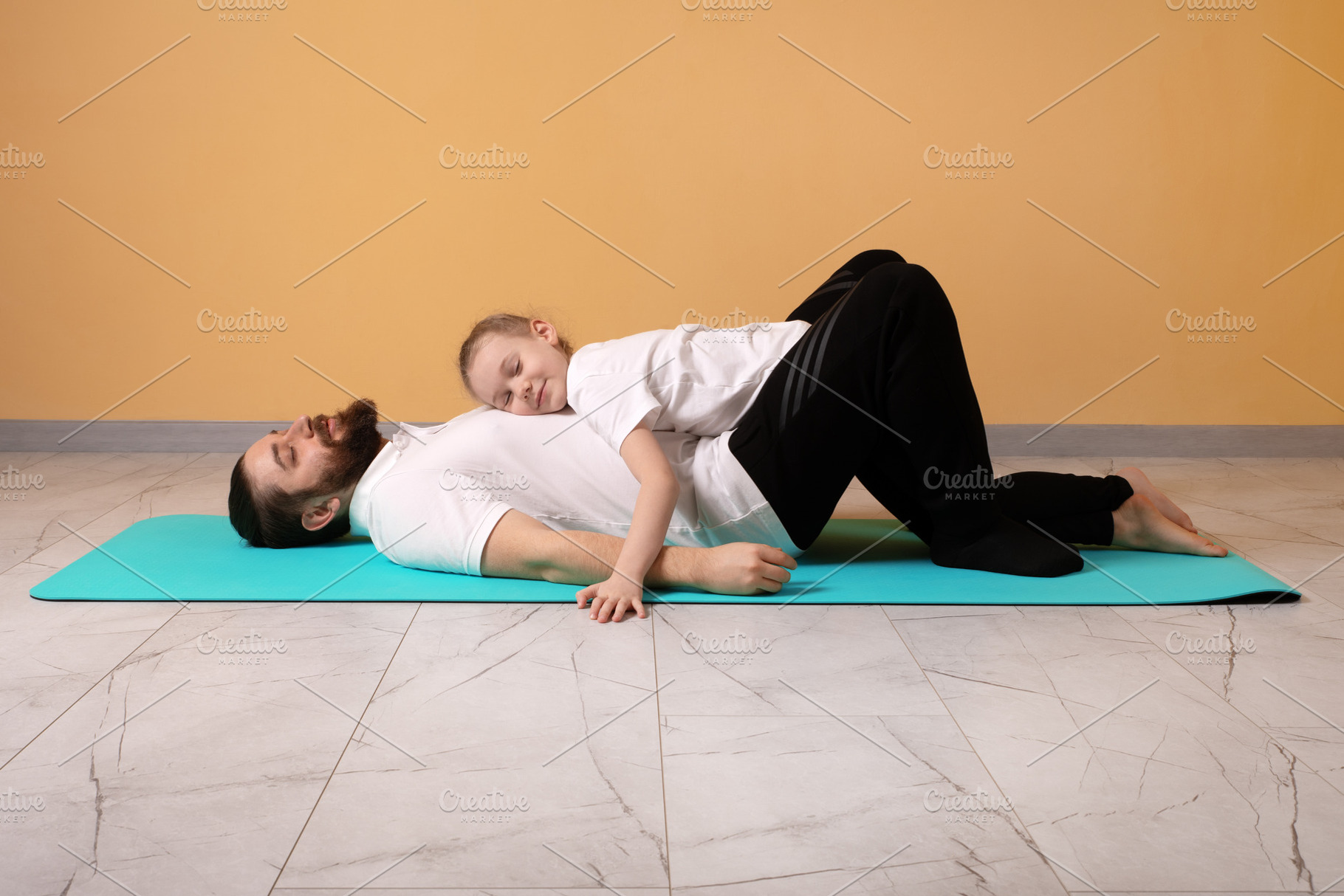 Young girl resting on her father’s chest as they lie on a blue, a Person Photo by Ales Munt