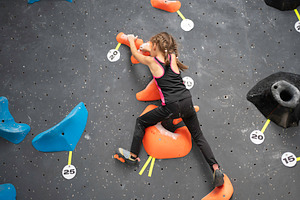 Courageous girl climbing artificial rock wall at bouldering gym, a Person Photo by andreonegin market