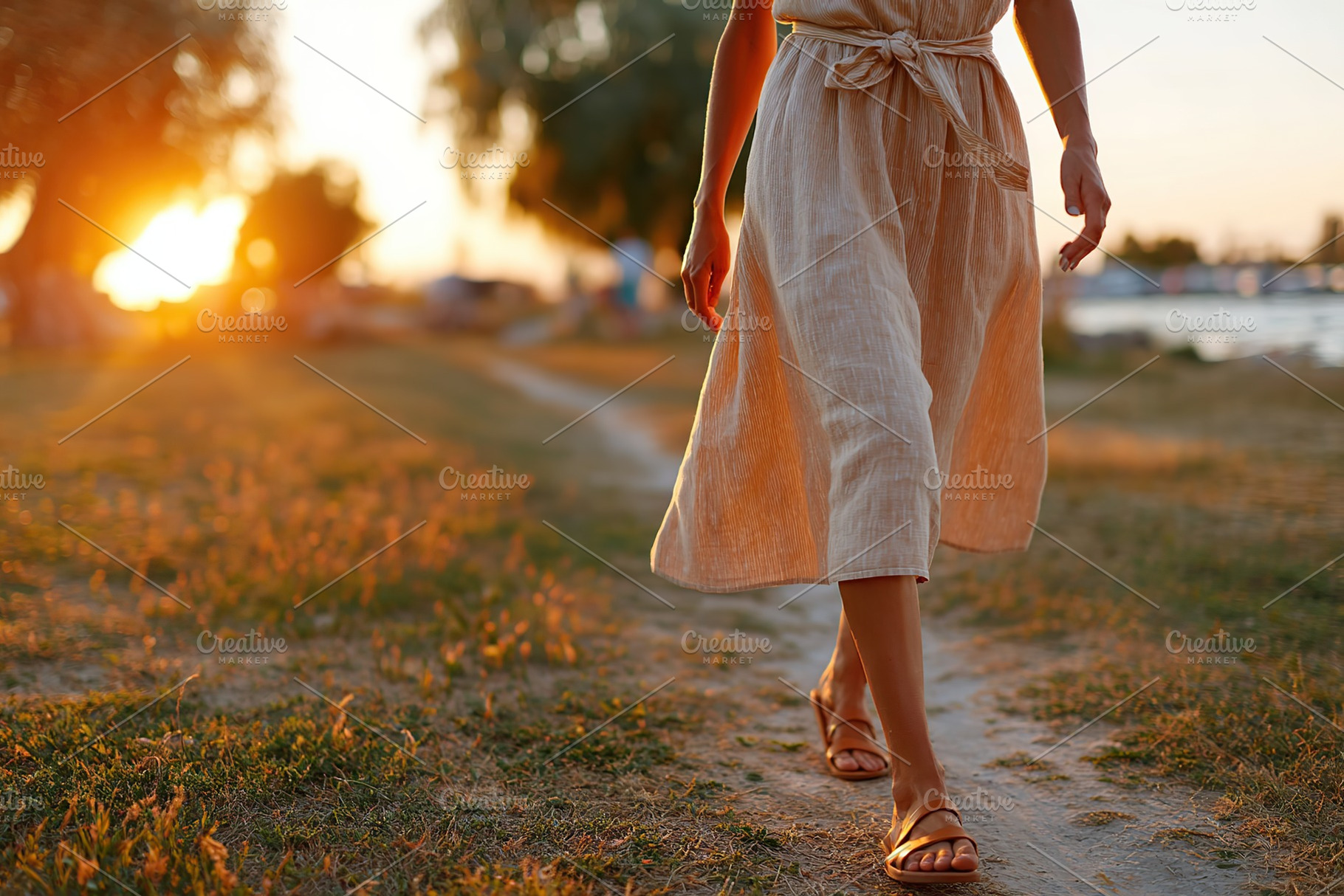 Woman in light linen dress and sandals walking along a scenic path during sunse, a Photo by AlyaAnd