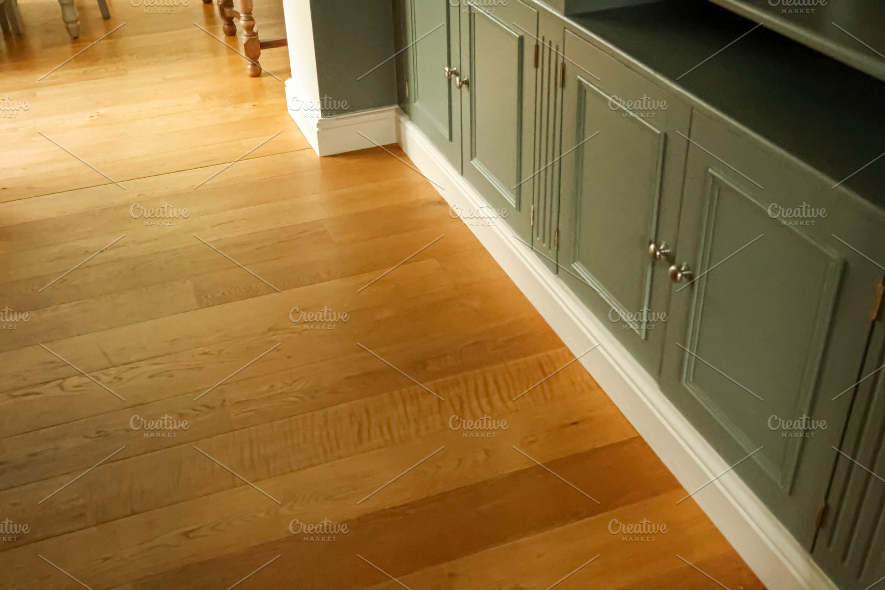 Hardwood flooring contrasting with sage green built in cabinetry and white base, a Photo by Studio ANNA