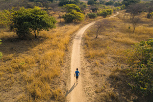 Boy runs down a narrow dirt path thr, a Photo by Iftikhar Alam