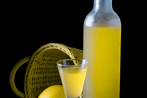 Italian limoncello in a shot glass on a black wooden background containing