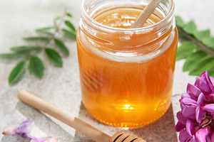Acacia honey jar on concrete with dipper and flowers, a Food & Drink Photo by Olena Rudo