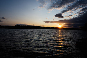 Serene sunset view over a tranquil lake with soft rippling water, a Photo by AS photostudio