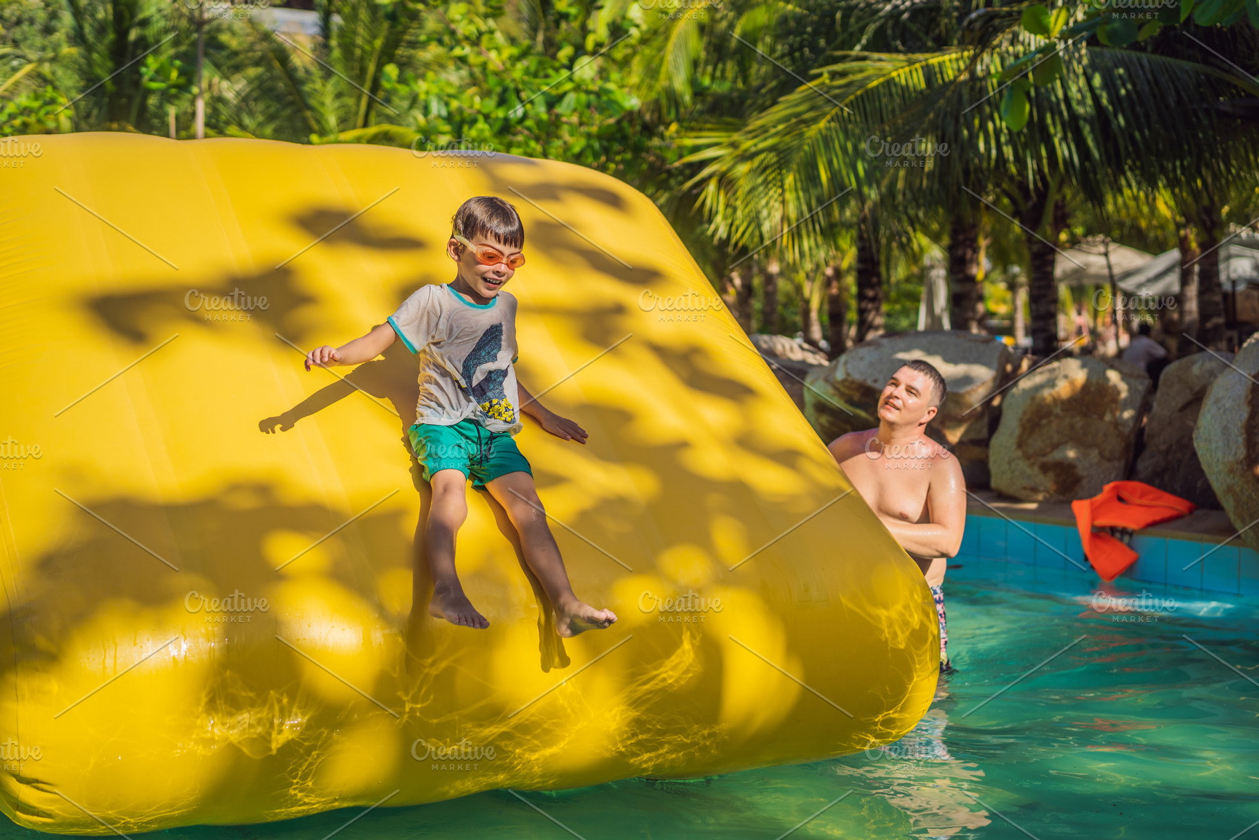 Dad and son go through an inflatable featuring boy, playground, and ...