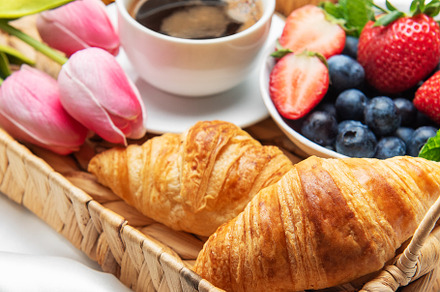 Romantic breakfast in bed with coffee, croissants, berries, hone