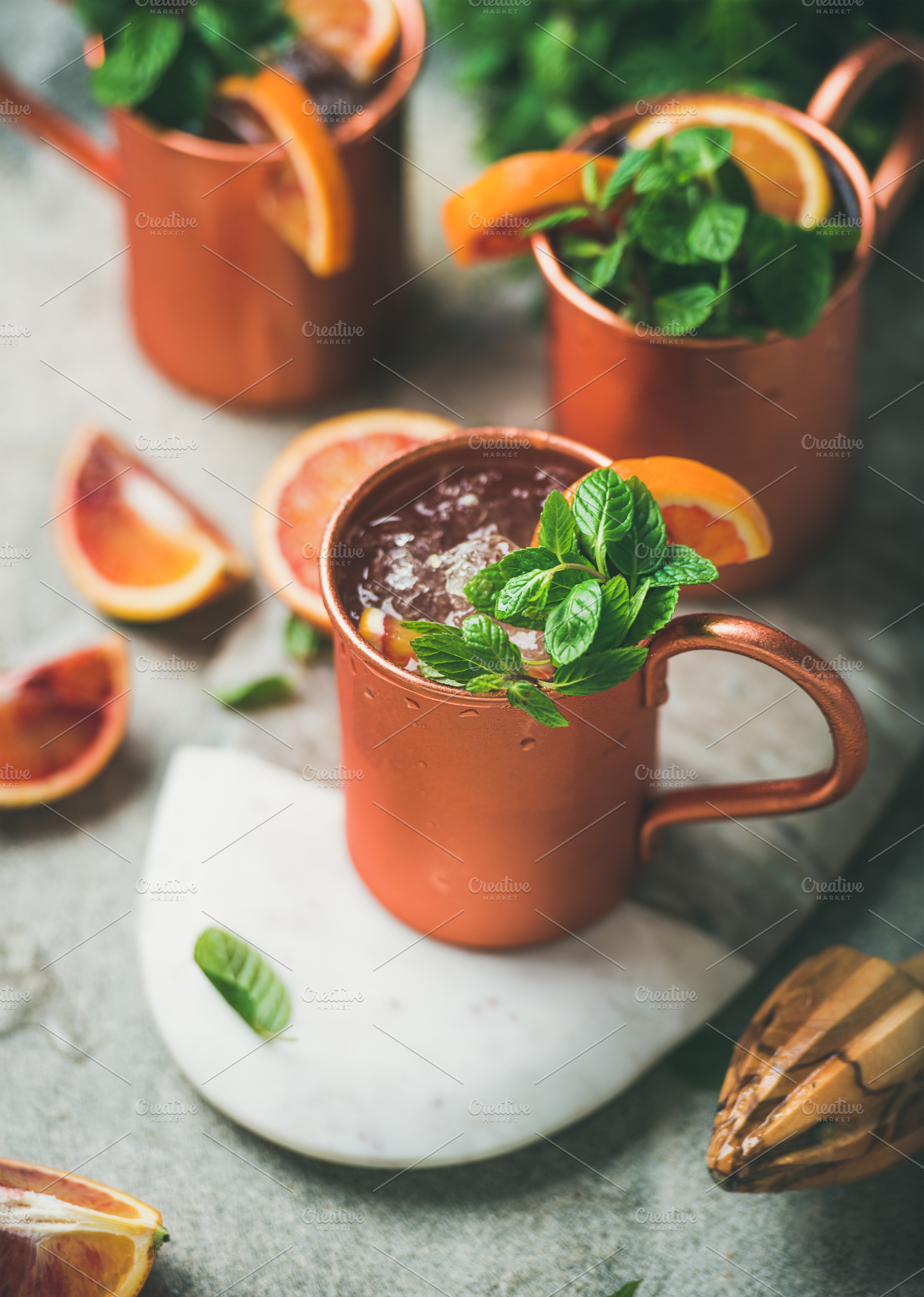 Blood orange Moscow mule alcohol cocktails in mugs on board, a Food & Drink Photo by Foxys