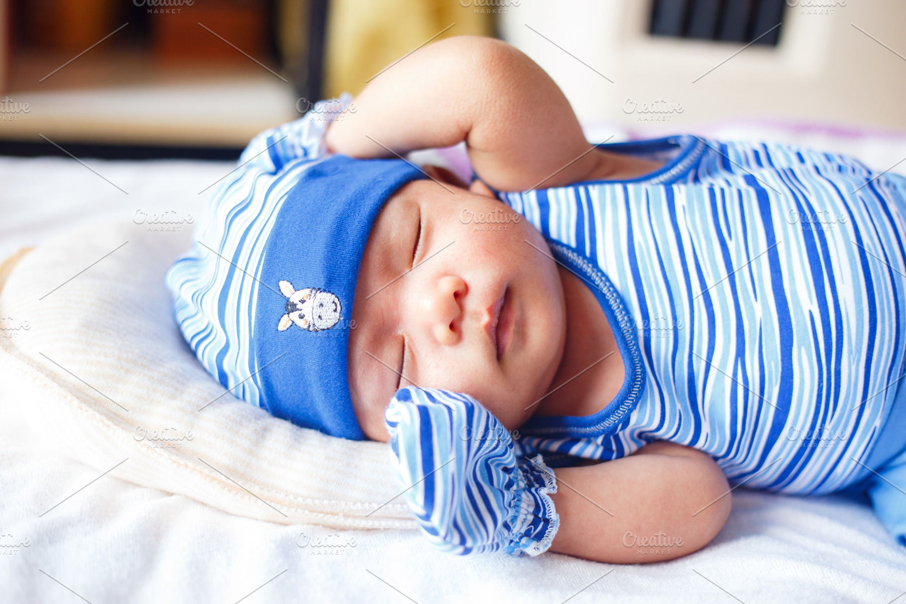 Sleeping baby in blue striped outfit and hat, peaceful expression, a Person Photo by a454
