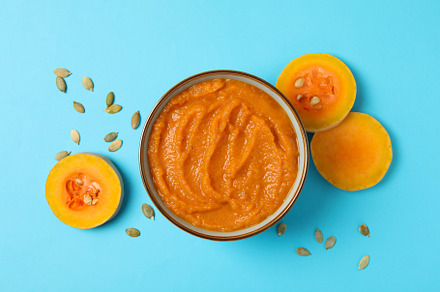 Bowl of pumpkin puree, seeds and slices on blue background, top, a Food & Drink Photo by AtlasStudio PRO