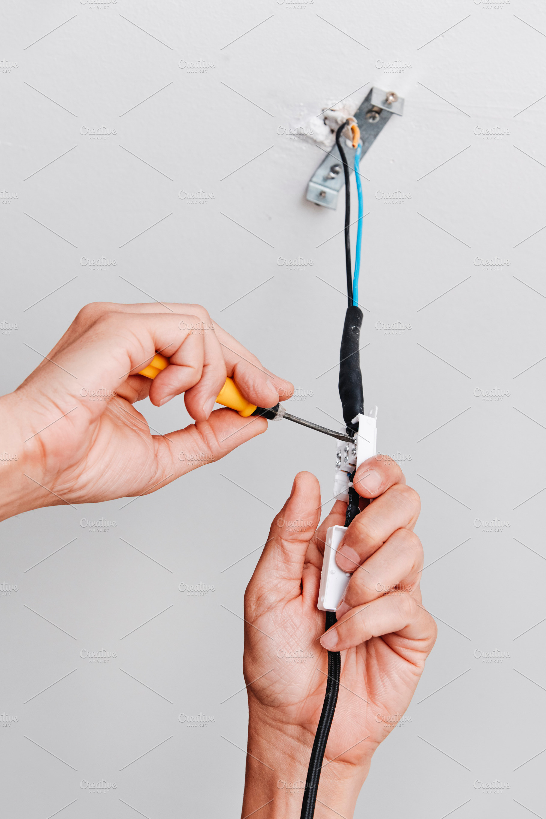 a man connects the electrical cord of a ceiling light, a Photo by Nito
